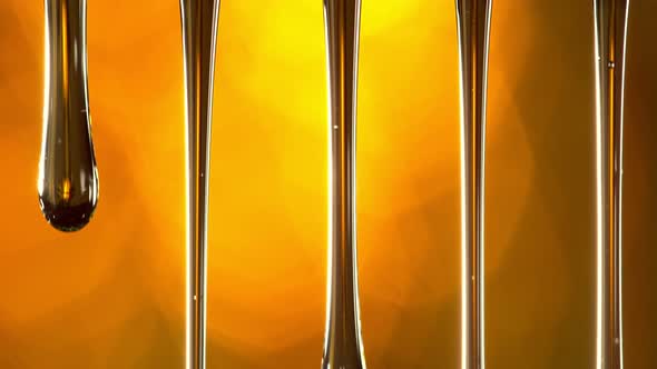 Super Slow Motion Macro Shot of Dripping Oil on Golden Background at 1000 Fps alt