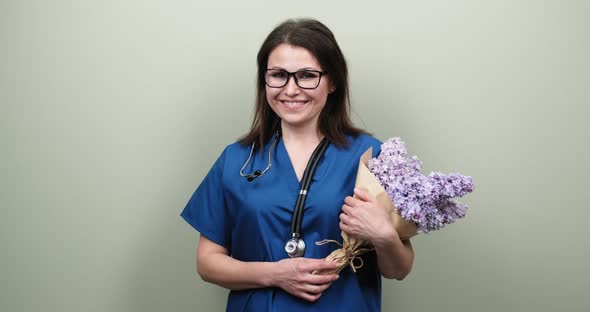 Portrait of Female Doctor Showing You Victory Sign, Happy Smiling Medic with Bouquet of Flowers  alt