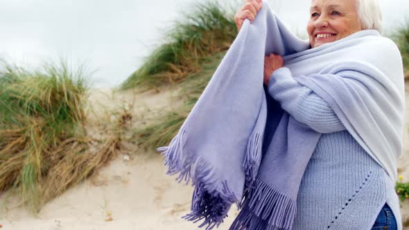 Happy senior woman in sweater feeling cold alt
