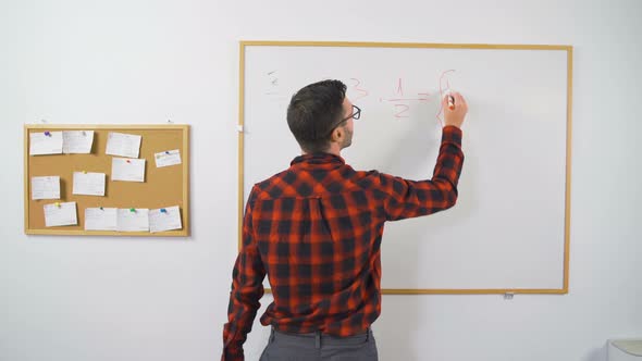 Young Male Math Teacher Writing Mathematical Equations on Whiteboard Using Red Marker for Online alt