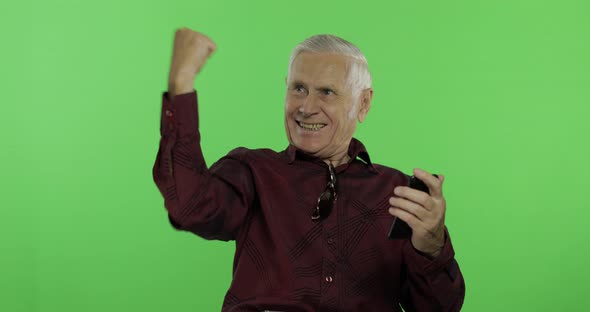 Senior Man Tourist Works on a Smartphone and Then Something Celebrates alt