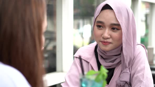 Asian hijab woman smilling in cafe with friend