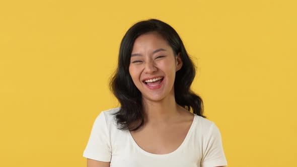 Happy young Asian girl in white plain t-shirt smiling and laughing