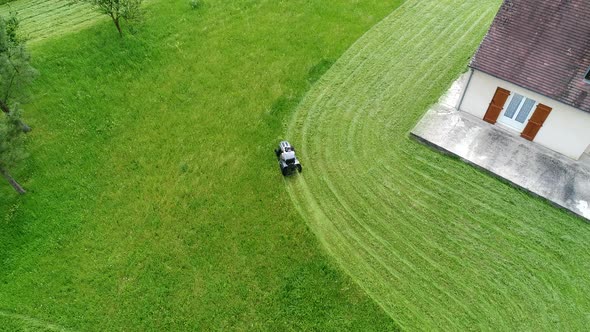 Riding lawn mower in action seen from the sky alt
