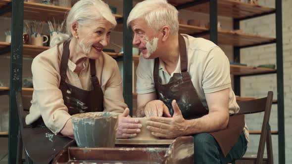 An Elderly Husband Helps an Elderly Woman During Pottery alt
