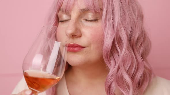 Beautiful Young Woman Drinking a Glass of Pink Wine Isolated Over Pink Background