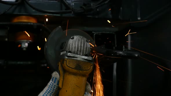 Mechanic Under a Car Using an Angle Grinder, in Slow Motion