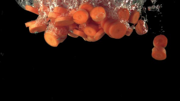 Super Slow Motion Pieces of Carrots Fall Under the Water alt