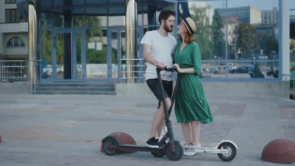 Lovely Couple Admiring Each Other on the Walk with Scooters in City alt