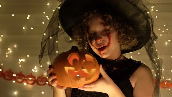 Portrait of a Teenage Girl Dressed As a Witch with Scary Makeup on Her Face alt