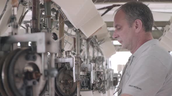 Worker working at a circular knitting machine in knitting factory alt