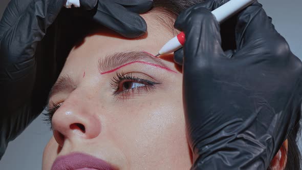 Beautician Drawing New Eyebrow Shape for Permanent Tattoo