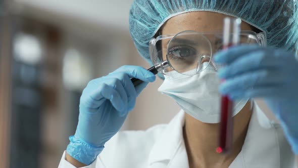 Female Medical Worker Looking at Blood Test Through Magnifying Glass, Analysis alt
