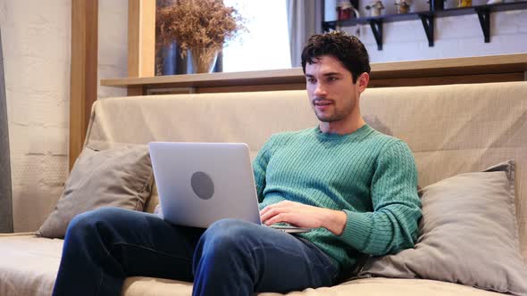 Man Celebrating Success While Working on Laptop Sitting on Couch alt