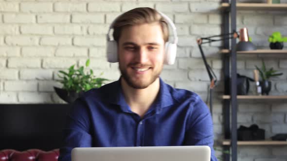 Happy young man wearing headphones having fun listening music. Smiling businessman sing song working alt