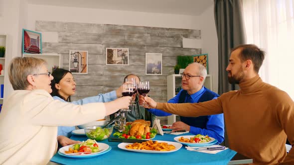 Young Man Clinking a Glass of Wine with His Family alt