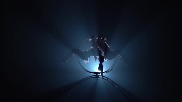 Professional Gymnasts Spin and Perform Various Stunts. Black Smoke Background. Silhouette. Slow alt