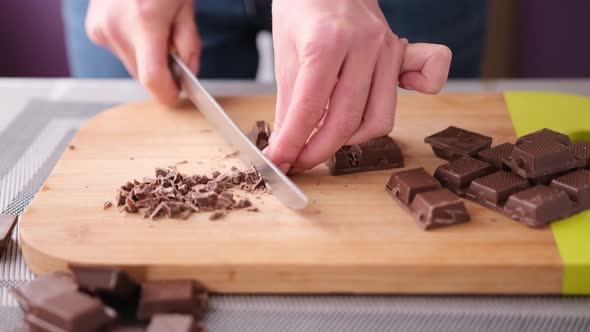 Woman Chopping Black Dark Chocolate on Wooden Cutting Board alt