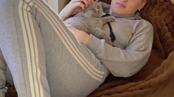 Girl is Reading a Book Near the Window with a Kitten in Her Arms alt