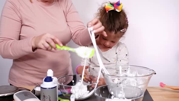 Step by step. Mother and daughter making colorful fluffy slime. alt