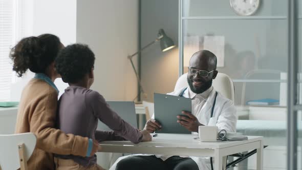 African American Pediatrician Giving Health Consultation to Boy and His Mom alt
