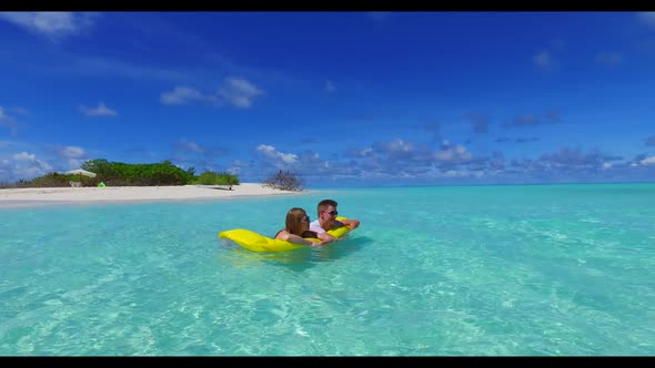 Boy and girl sunbathing on exotic resort beach holiday by blue lagoon with bright sand background of alt