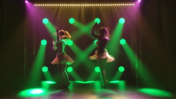 Two Attractive Girls Are Dancing in Hawaiian Costumes and Lei Wreaths. Hawaiian Style Party alt