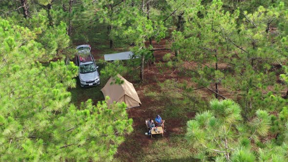Aerial view of Asian couple camp enjoying, relaxing nature in the pine forest