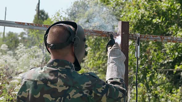 Slow Motion Backside Builder Welds Upper Parts of Fence alt