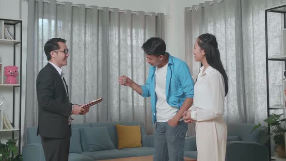 Asian Man Receiving The Keys From A Real Estate Agent Before Showing To A Woman alt