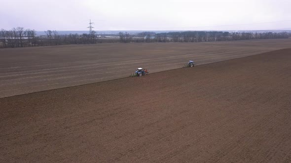 Agricultural Work in the Field, Two Blue Tractors Plow the Land