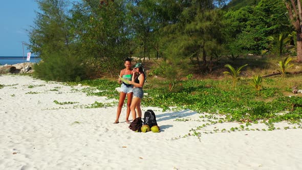 Women enjoying life on tropical island beach journey by blue green ocean with white sandy background alt
