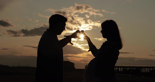 Smiling Husband and Pregnant Wife Posing in Bright Sunlight