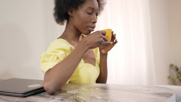 Beautiful African American Woman Drinks Tea in Kitchen