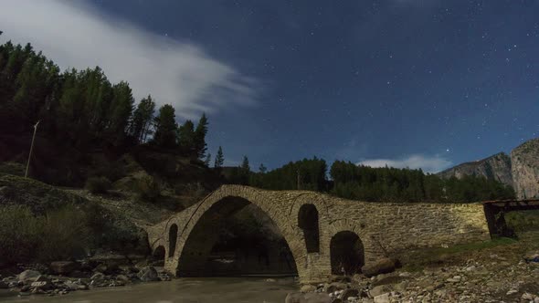 Time lapse of stars moving on the night sky over a typical old stone Arch Bridge, Albania