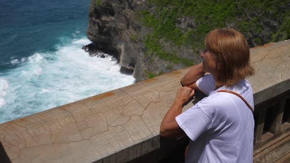 Back View of Middle Aged Woman Contemplating the Beauty of the Ocean on Frim an Observation Dock alt