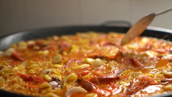 arranging the distribution of the mixture by the paellon with a kitchen shovel alt