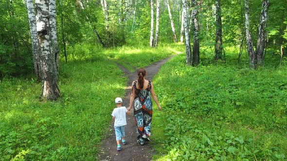 A Young Mother with a Child Walking in the Park alt