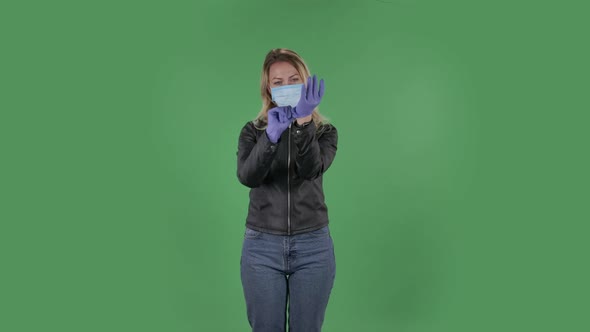 Portrait of Beautiful Young Woman in Medical Mask Is Looking at Camera and Puts on Rubber Gloves alt