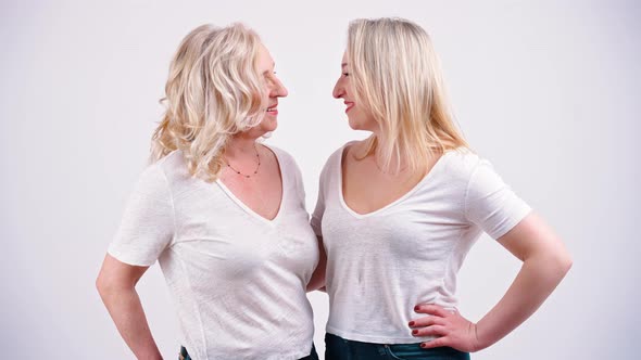 Studio Shot on White Background of Two Similarly Looking Middleaged Women Standing Close to Each alt