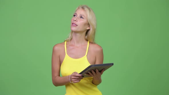 Young Happy Beautiful Blonde Woman Thinking While Using Digital Tablet