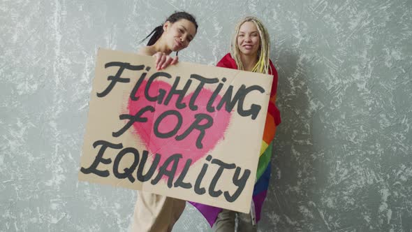 Teenage Girl Hugs and Covers Her Girlfriend with a Rainbow Flag alt