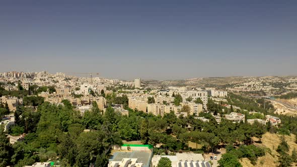 Aerial fly over Jerusalem suburb neighborhood at warm day,green trees growing between the buildings. alt