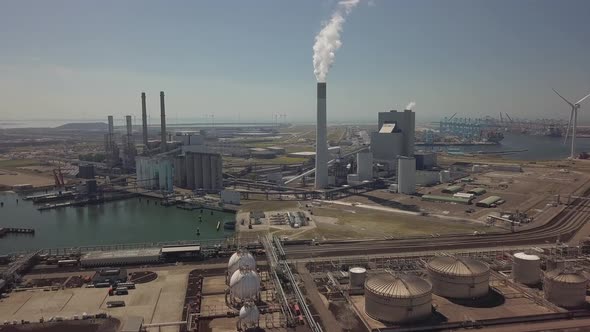 Tower with smoke in industrial harbor of Rotterdam in the Netherlands, Aerial alt