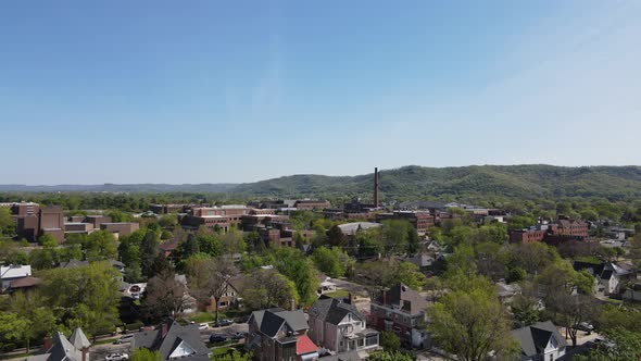 Bright blue sky over trees lined streets with mountains and forests in the background.