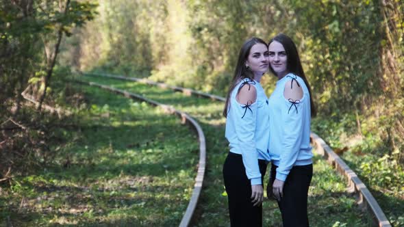 Smiling Young Twins Women Standing Together on Railroad alt