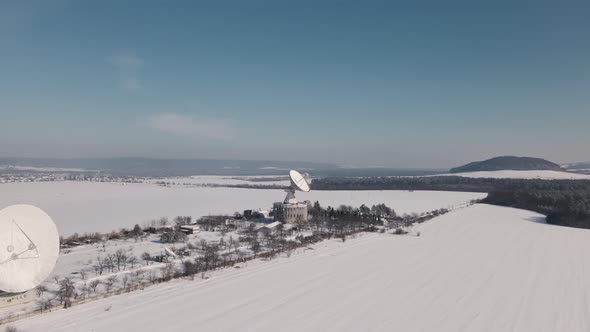 Cinematic Aerial View of the Space Communication Station in Snow Covered Field at Sunny Winter Day