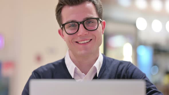 Young Businessman with Laptop Smiling at the Camera  alt