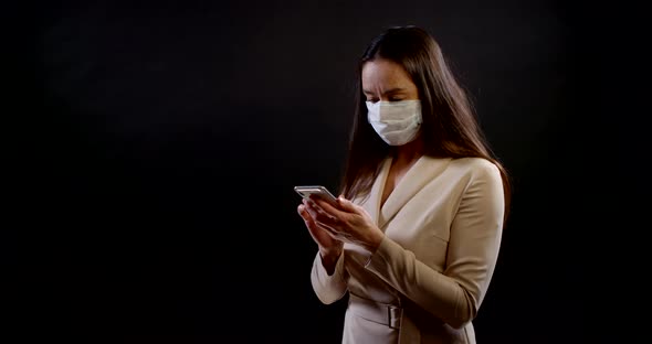 Portrait of a Woman on a Black Background. She's Wearing a Disposable Face Mask, Standing Three alt
