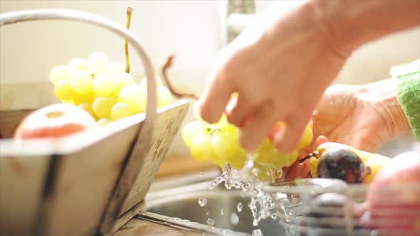 Woman washing grapes at kitchen sink